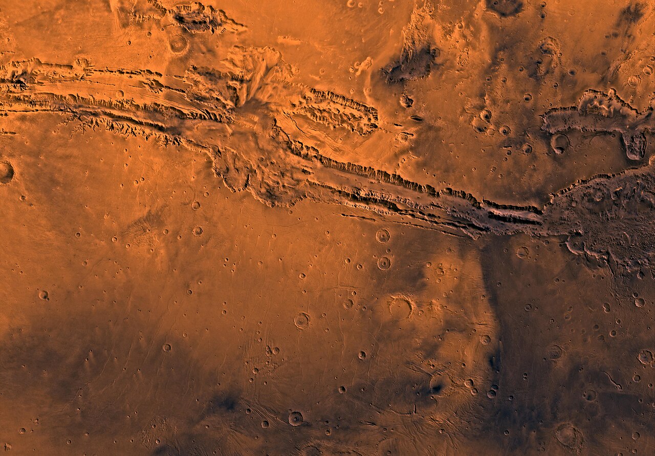 Mosaico de imágenes orbitales del sistema de cañones Valles Marineris en Marte, con relieve de color naranja y cráteres