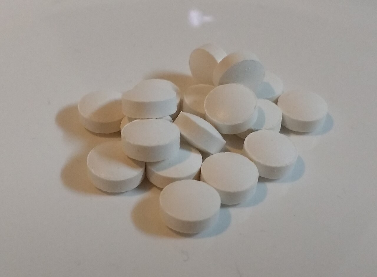 Un montón de pastillas blancas de vitamina D sobre una superficie clara