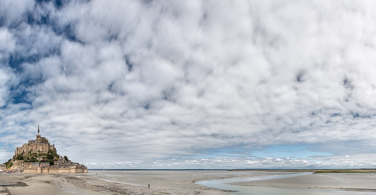Bahía del Mont-Saint-Michel, en Francia, con la marea baja: arena y canales de agua a los pies del islote con la abadía