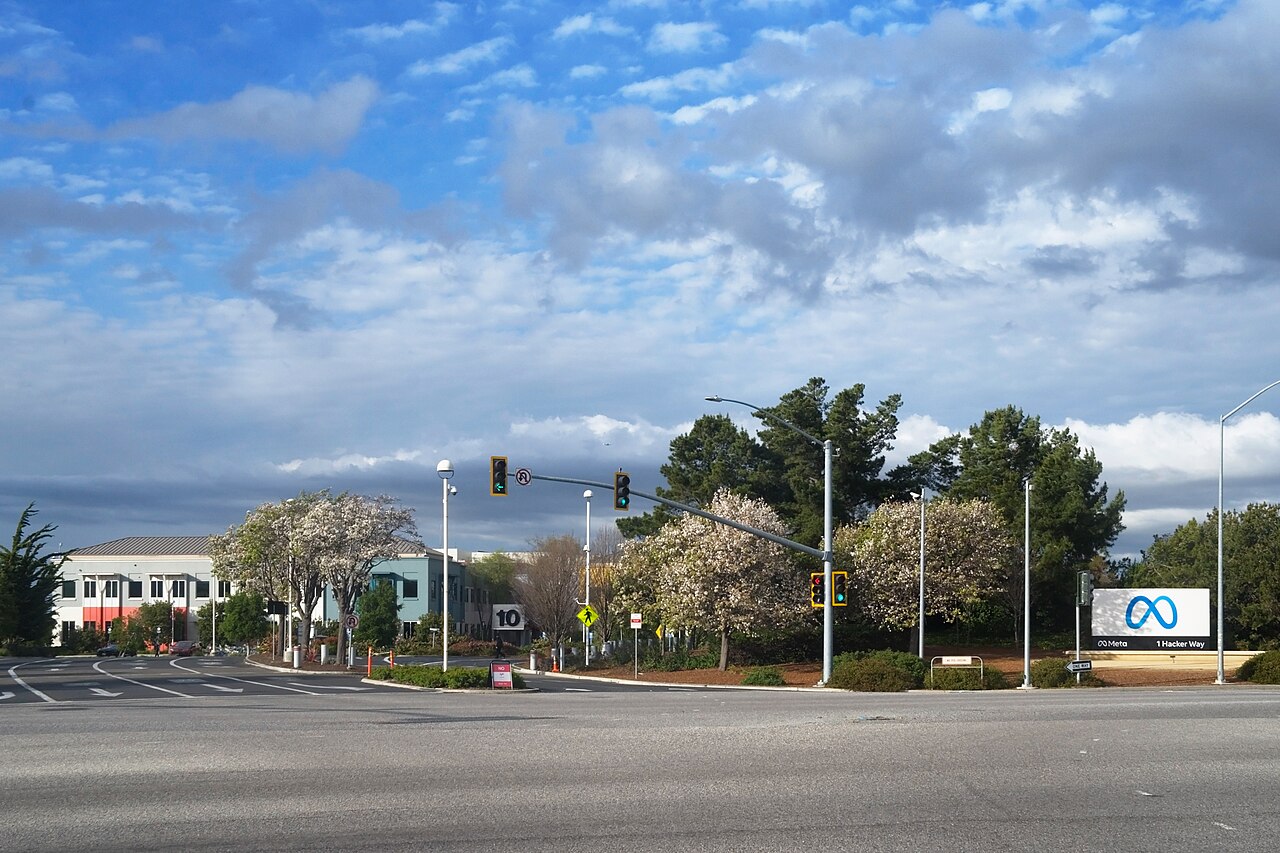 Cartel de Meta en la entrada de la sede de la empresa, en Hacker Way 1, Menlo Park, California, junto a una carretera con semáforos