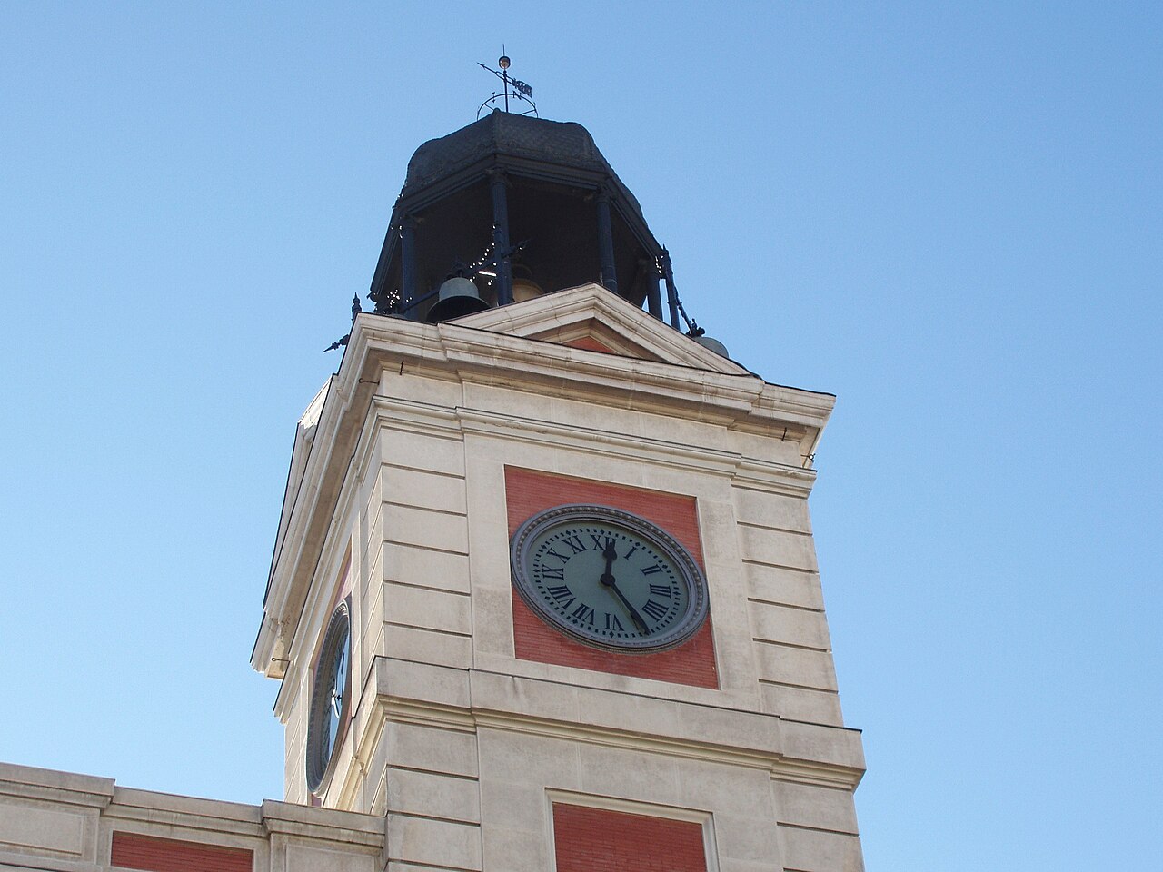Reloj de la torre de la Casa de Correos en la Puerta del Sol de Madrid, visto desde abajo contra un cielo azul