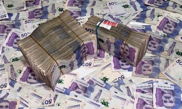 Fajos de billetes colombianos de 50.000 pesos sobre una superficie cubierta de billetes
