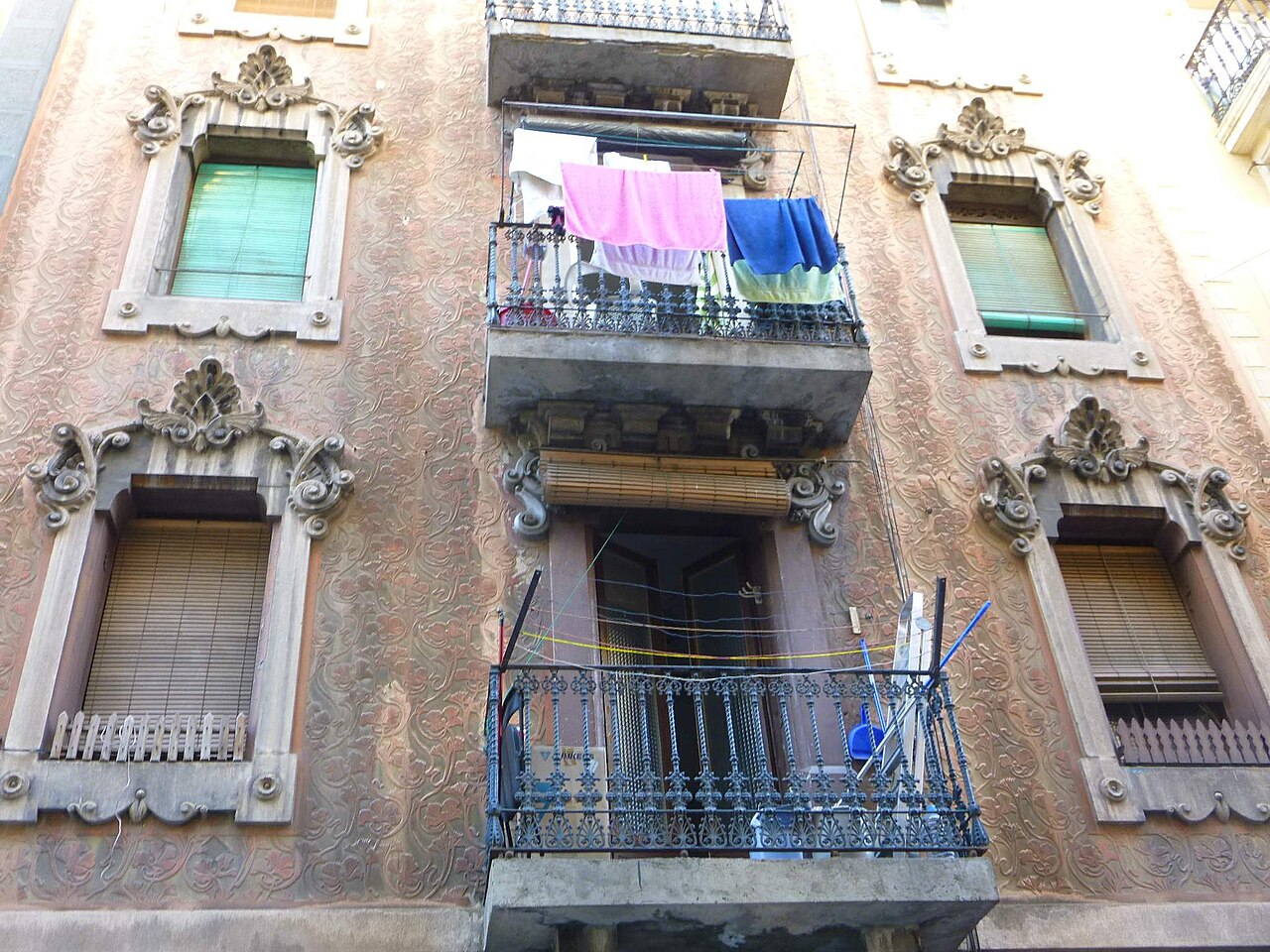 Fachada de un edificio de viviendas con balcones y ropa tendida en el barrio de la Barceloneta, en Barcelona