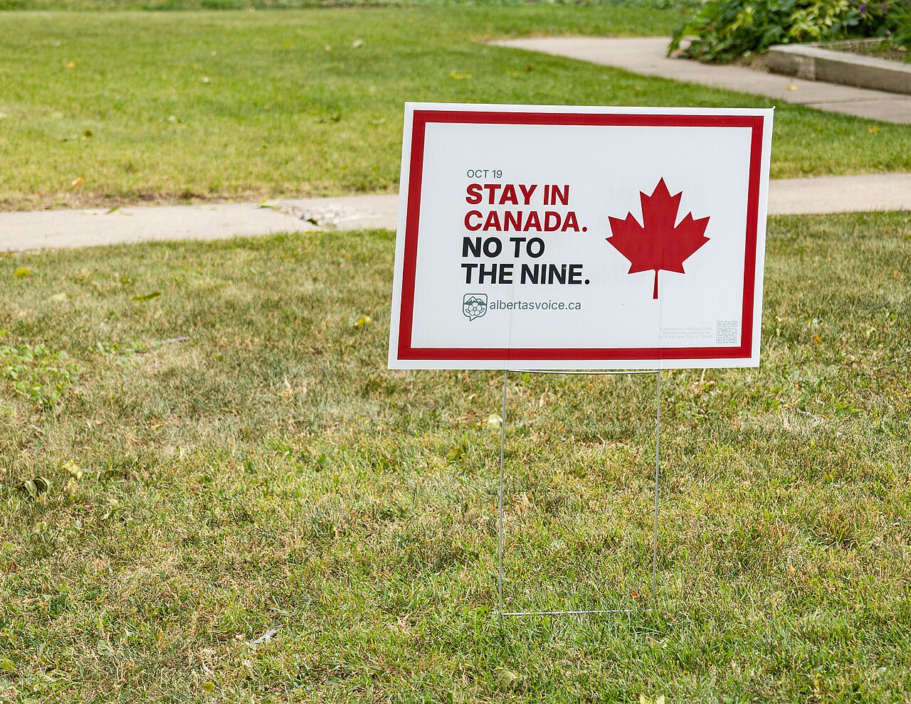 Cartel de campaña en un jardín de Edmonton, con una hoja de arce y el mensaje de permanecer en Canadá, antes del referéndum del 19 de octubre de 2026
