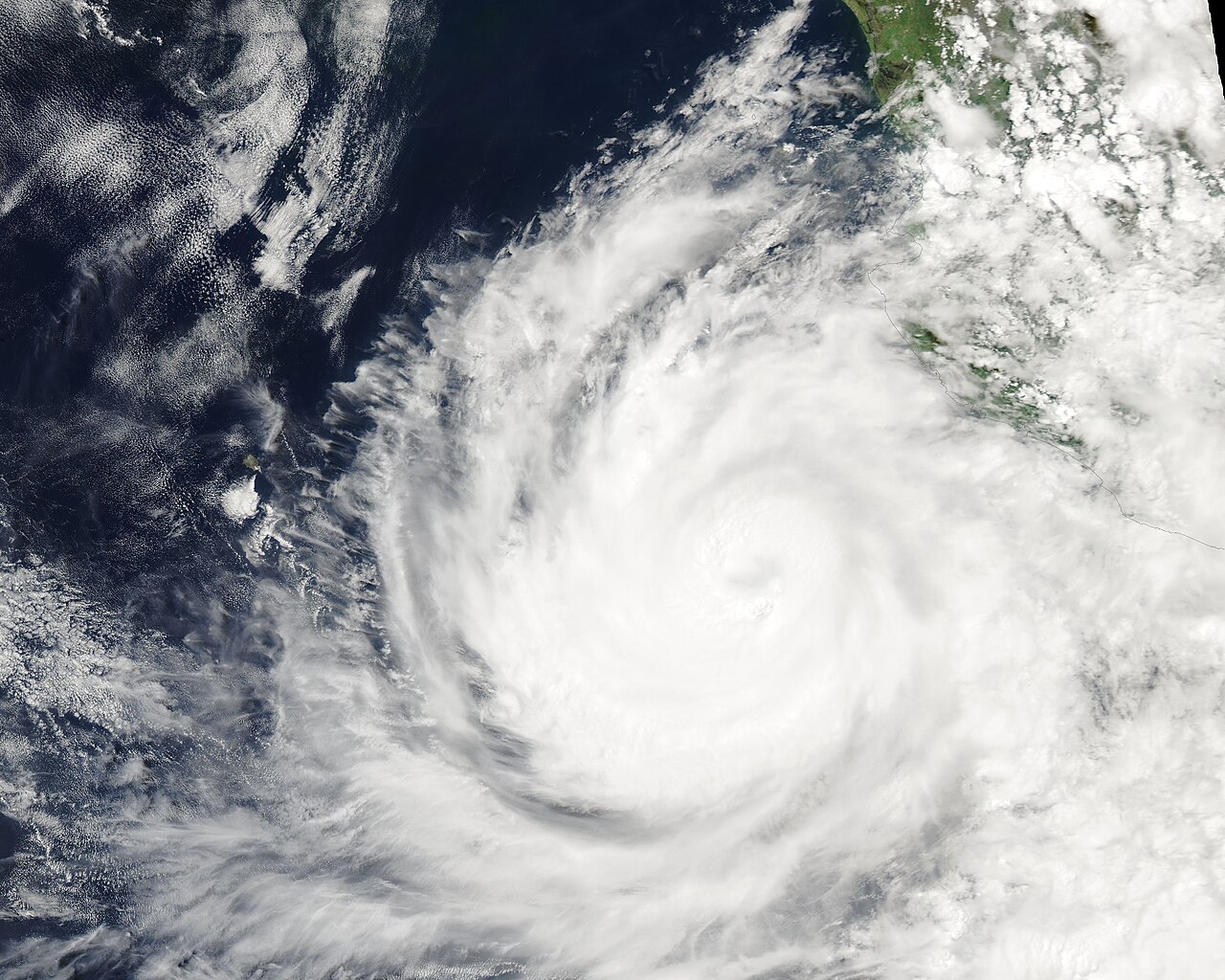 Imagen de satélite de un huracán, una gran espiral de nubes blancas con ojo, frente a la costa del Pacífico de México
